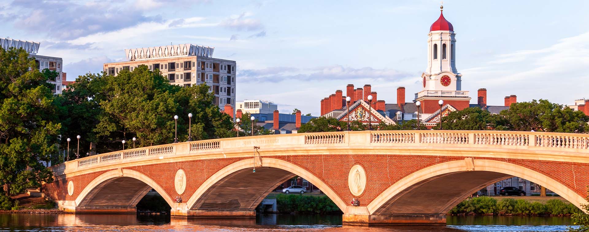 Arch bridge on the Harvard campus over the Charles River with a view of Boston behind it