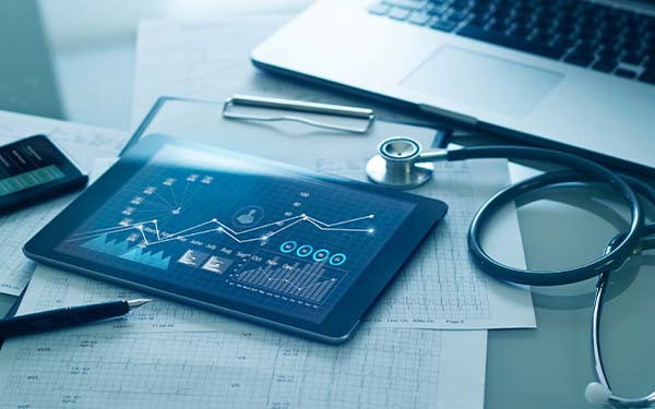 A desk with medical charts, a tablet, and a stethoscope