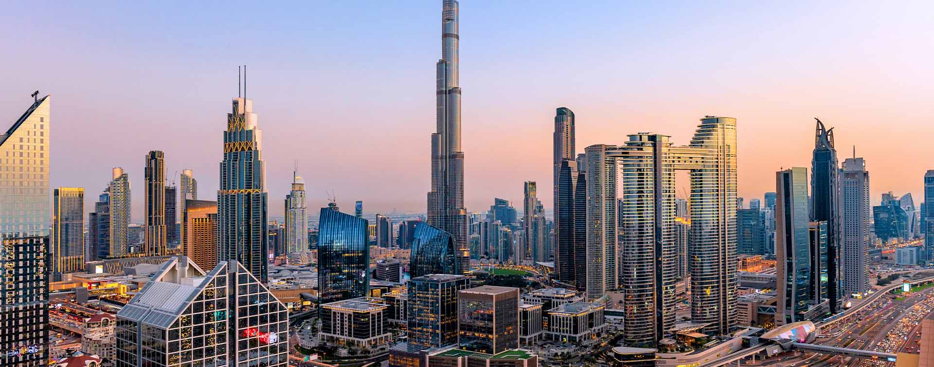 Dubai at sunset with modern skyscrapers, illuminated highways, busy traffic and dense urban development