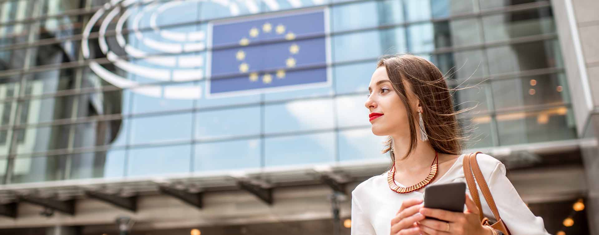 Woman standing near European Union building with flag