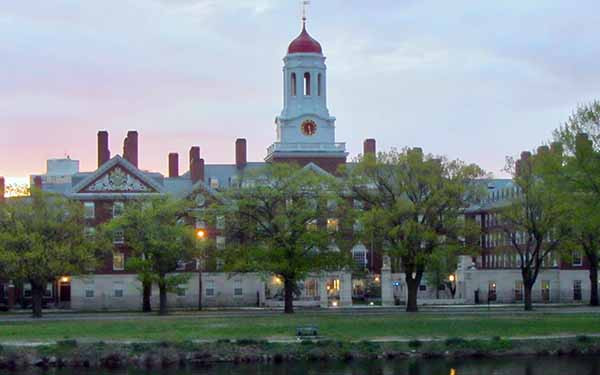 University campus with clock tower by a river at sunset