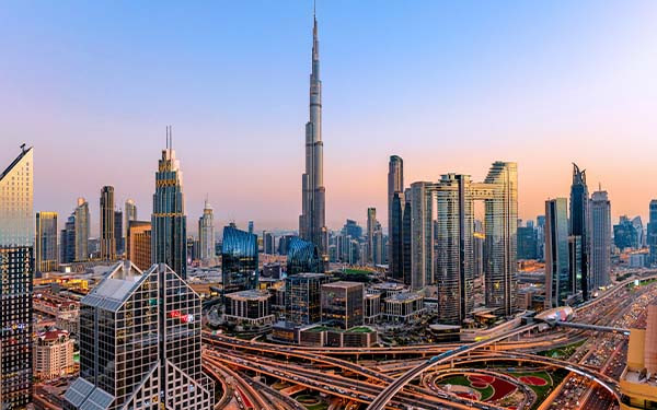 Dubai at sunset with modern skyscrapers, illuminated highways, busy traffic and dense urban development