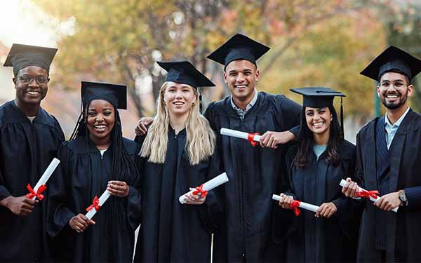 Group of graduates in caps holding diplomas