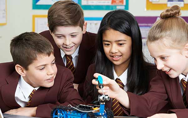 School children building a robot in classroom