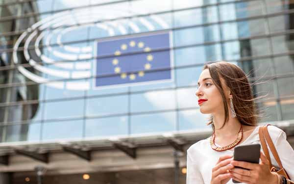 Woman standing near European Union building with flag