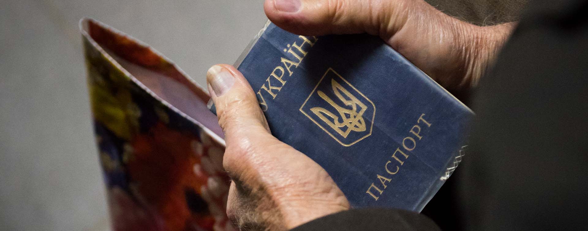 Elderly male hands holding a Ukrainian passport