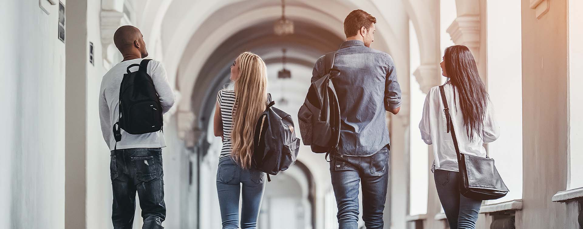 University students carrying backpacks walking in a corridor 