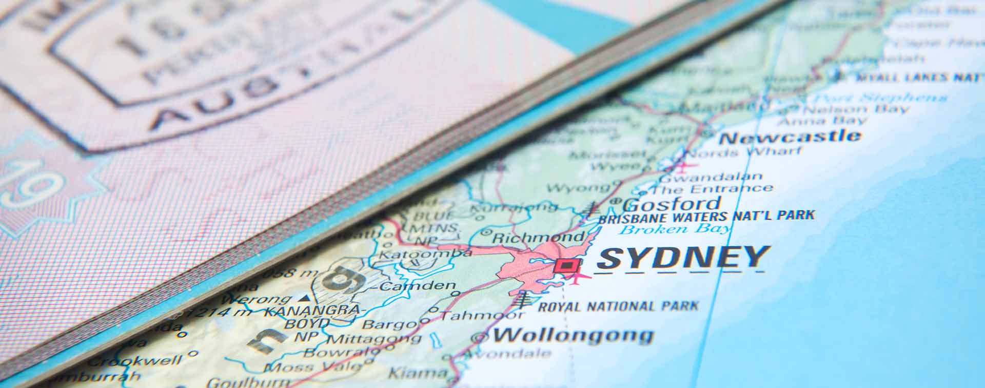 Extreme close-up of a map of Australia showing Sydney and a partial Australian passport lying over it.