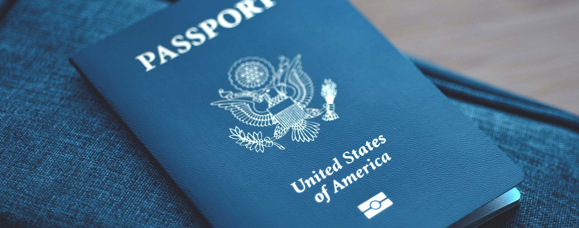 US passport on a blue travel bag against a wooden floor