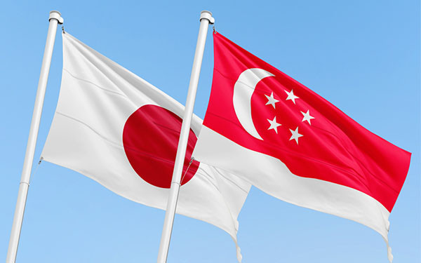 Singaporean and Japanese flags flying over a clear blue sky