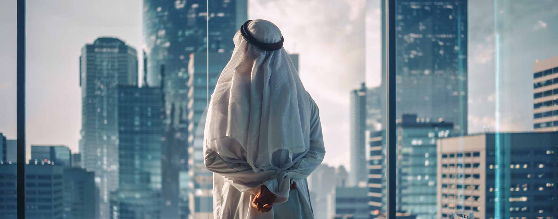 Arab businessman looking at a skyline contemplatively through a window