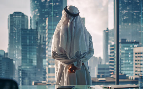 Arab businessman looking at a skyline contemplatively through a window