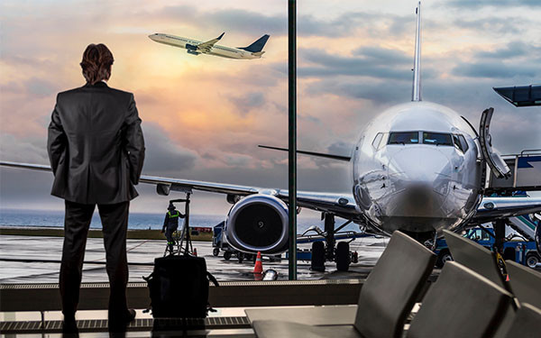 A businessman admiring planes through a window at the airport
