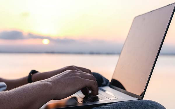 Man working on laptop in front of ocean view