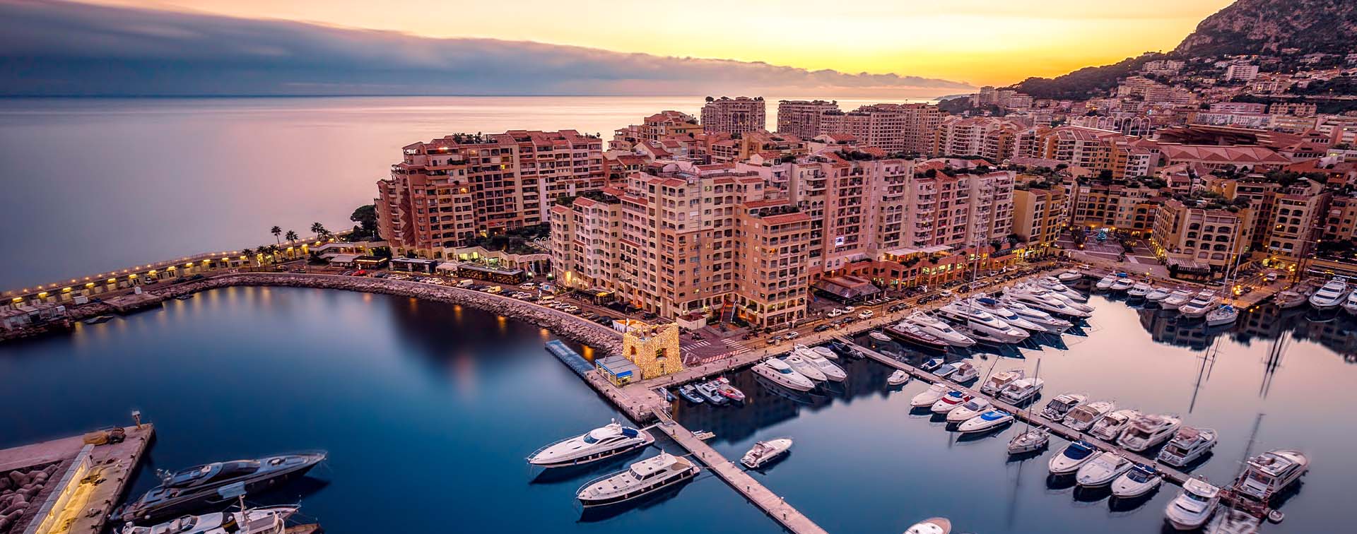 Scenic marina with luxury yachts and waterfront buildings at sunset