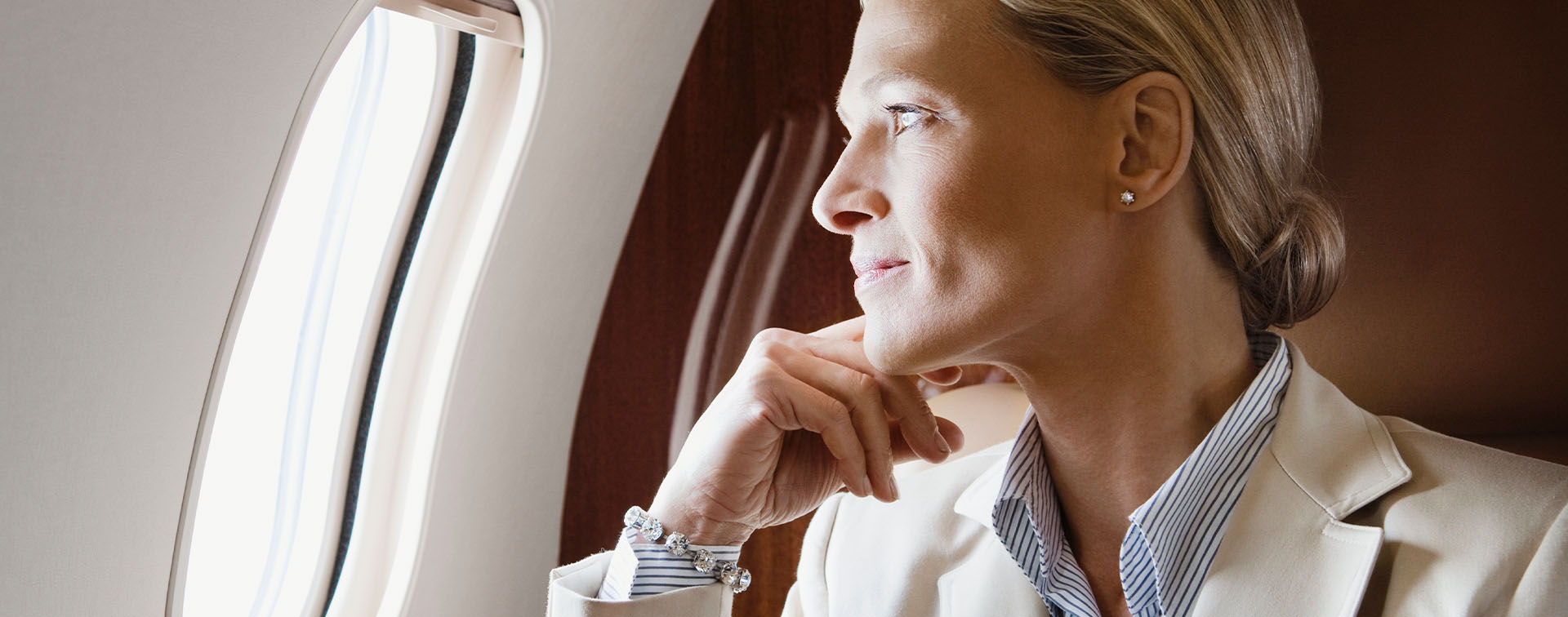 Wealthy businesswoman sitting in a plane gazing out of window