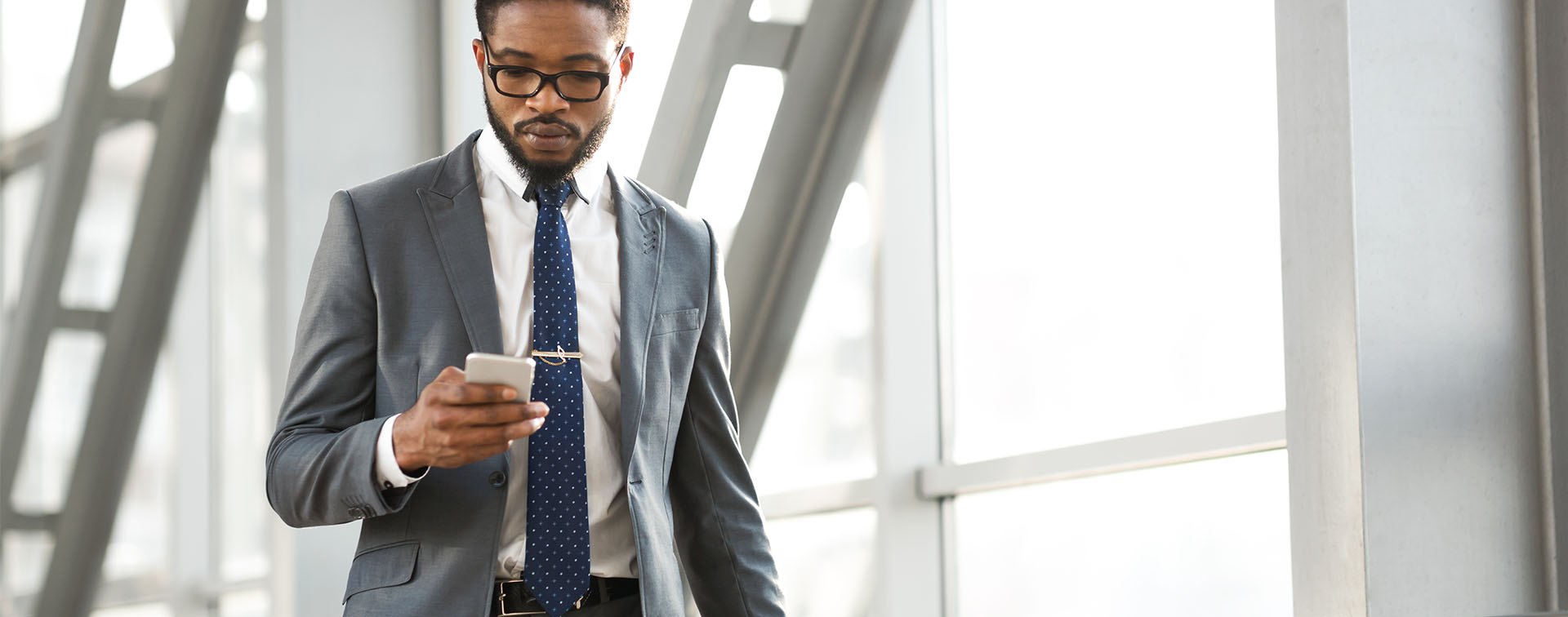 Businessman walking through airport while checking mobile phone