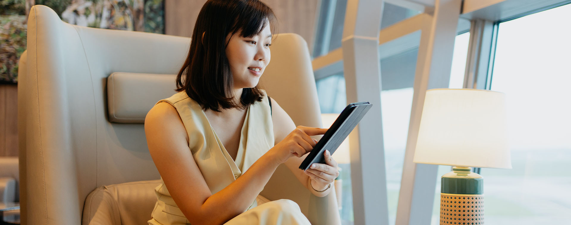 Affluent Asian woman in travel lounge using a tablet