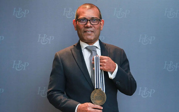 Global Citizen Award winner Mohamed Nasheed holding medal against an H&P-branded backdrop