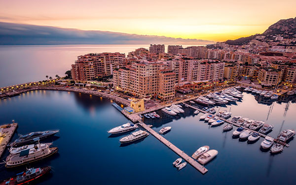 Scenic marina with luxury yachts and waterfront buildings at sunset