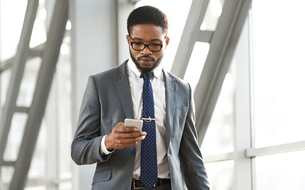 Businessman walking through airport while checking mobile phone