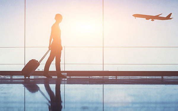 Traveler with a suitcase walking in an airport as a plane takes off