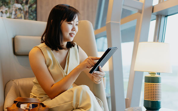 Affluent Asian woman in travel lounge using a tablet