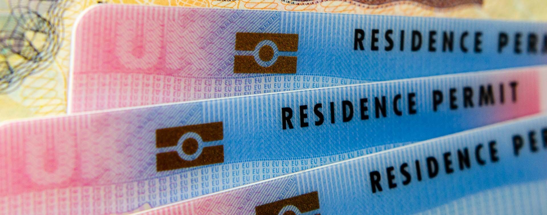 Biometrical Residence Permit cards for Tier 2 work visa placed on top of UK Entry Clearance vignette sticker in passport