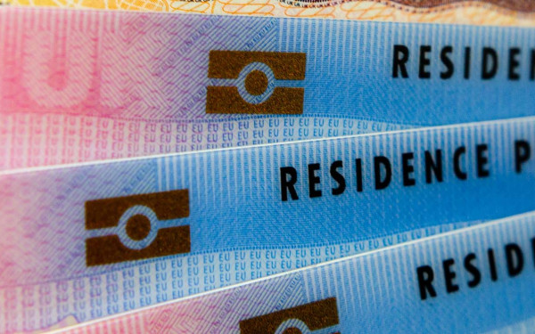 Biometrical Residence Permit cards for Tier 2 work visa placed on top of UK Entry Clearance vignette sticker in passport