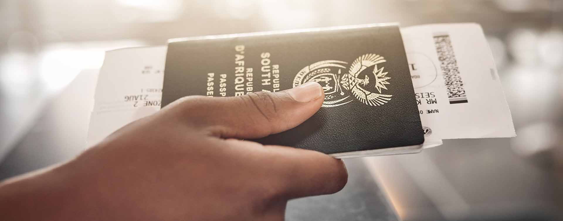 South African passport containing flight ticket held in hand