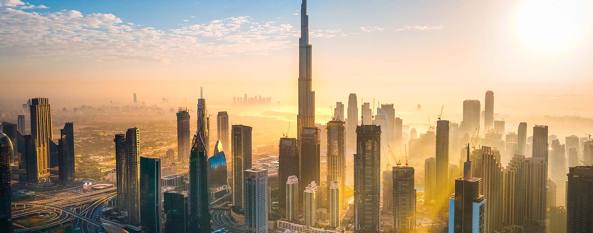 Dubai skyline with the Burj Khalifa in the center and sunshine spreading between the buildings