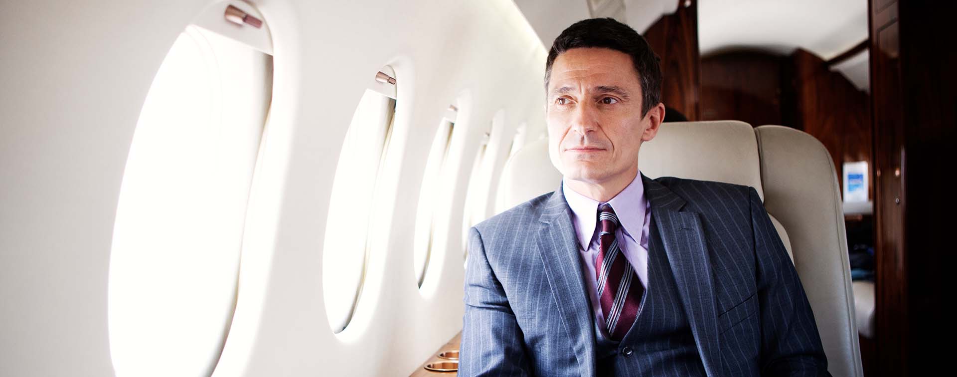 Caucasian business man sitting in a private airplane staring out the window