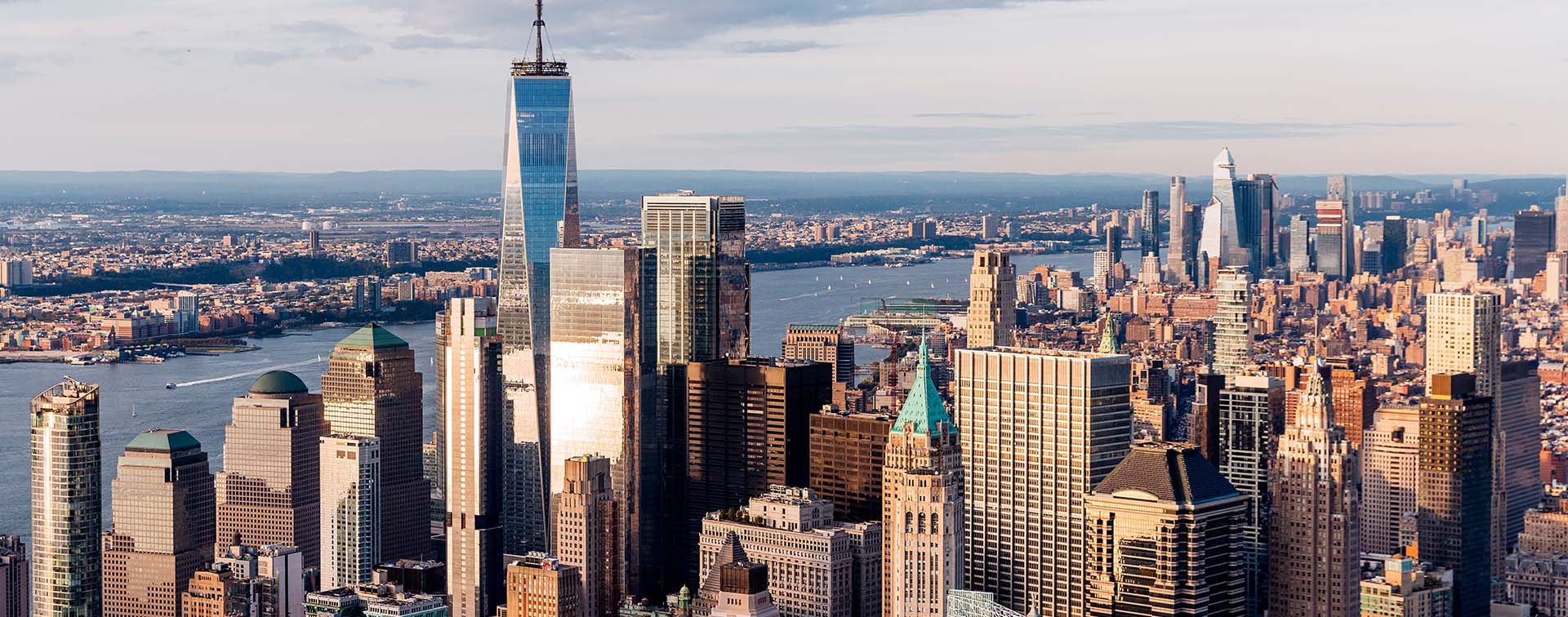 New York City skyline seen from a high angle, featuring the One World Trade Center and the Hudson River 