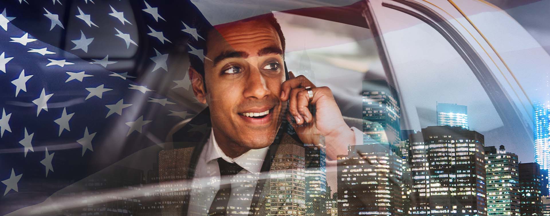 Businessman in a suit on mobile phone in cab with New York City buildings and US flag in the background