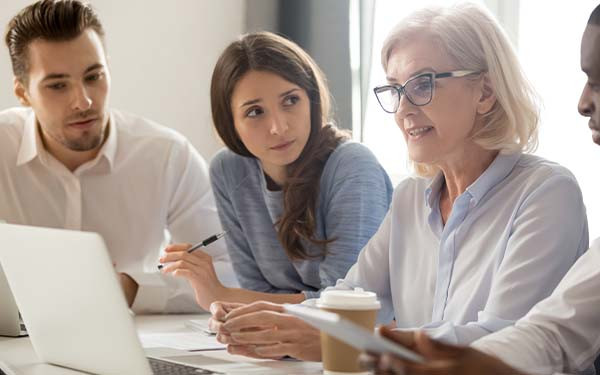 Focused young interns making notes listening to manager