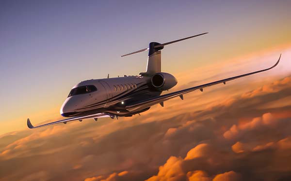 A luxury private jet flying over cloudy skies at sunset