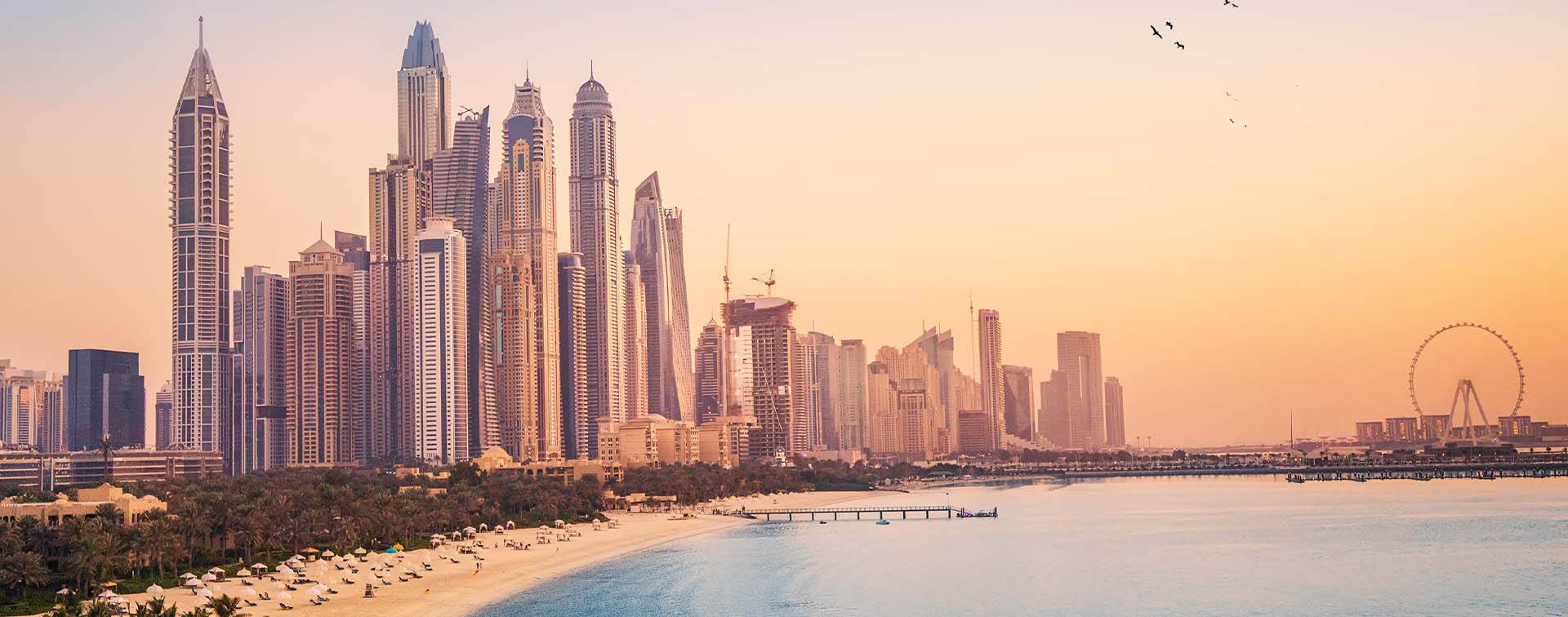 Sunset view of Dubai Marina and Jumira Beach Residence area with ferris wheel and golden sand beaches in the Persian Gulf