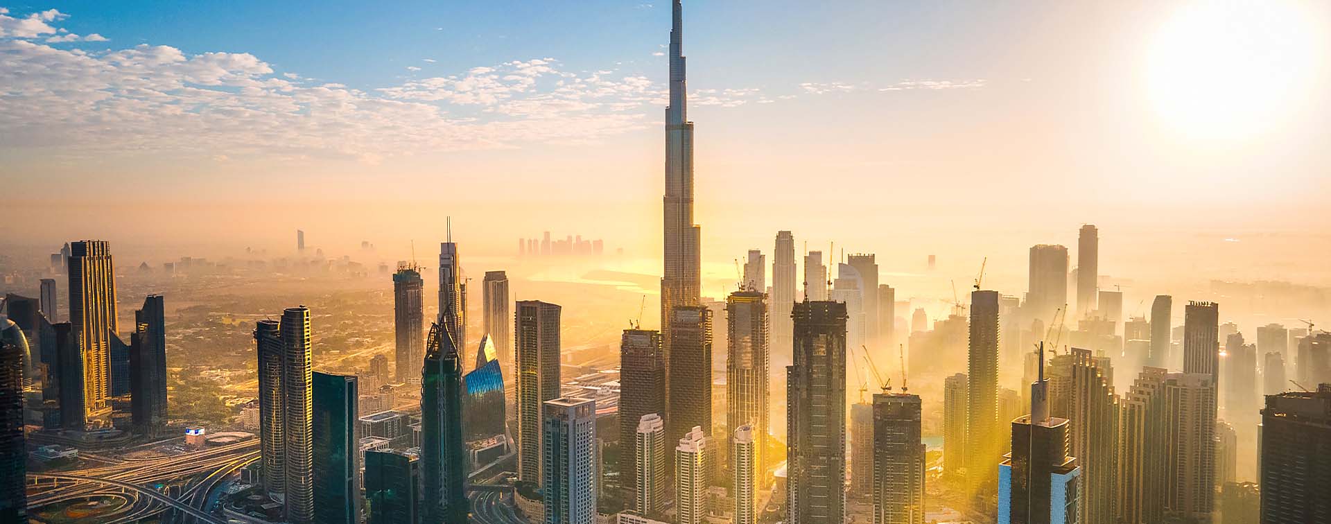 Skyline in Dubai, UAE, illuminated by a glowing sun