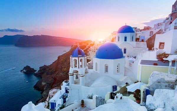 Blue domed churches at sunset in Oia, Santorini